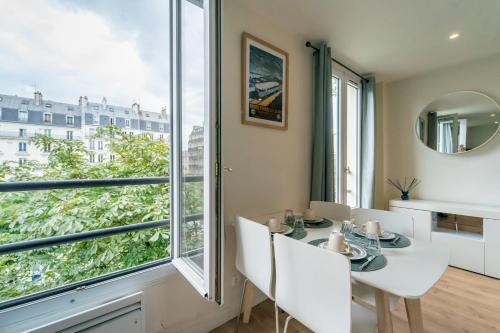 une salle à manger avec une table et une grande fenêtre dans l'établissement GH Apartment Pasteur-Montparnasse, à Paris