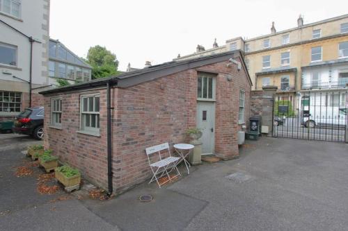 a small brick building with a chair in a parking lot at The Coach House, Clifton and Parking - Hopewell in Bristol