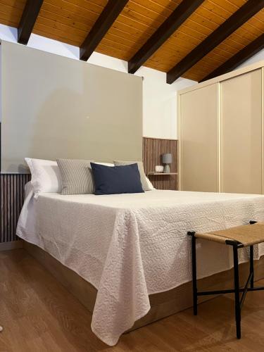 una camera da letto con un grande letto con lenzuola bianche e cuscini blu di San Antonio 6 a Malpartida de Cáceres