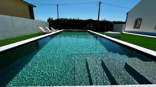 a swimming pool with two chairs in a yard at OceanLand - Santa Cruz in Santa Cruz