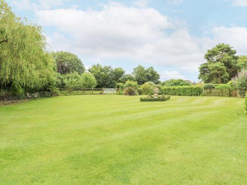 a large grassy yard with a fence and trees at The Barn in Ashill