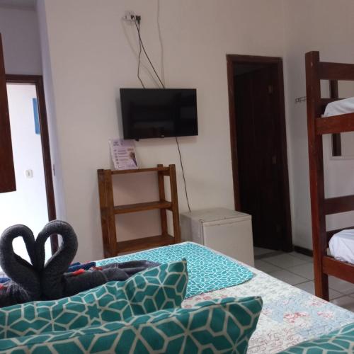 a room with a bed and a tv and a table at Pousada Pura vida in Itacaré