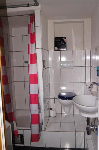 a bathroom with a red and white shower curtain and a sink at Mitten im Garten in Friedland