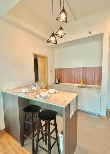 a kitchen with a large island with two bar stools at imperium residence kuantan in Kuantan