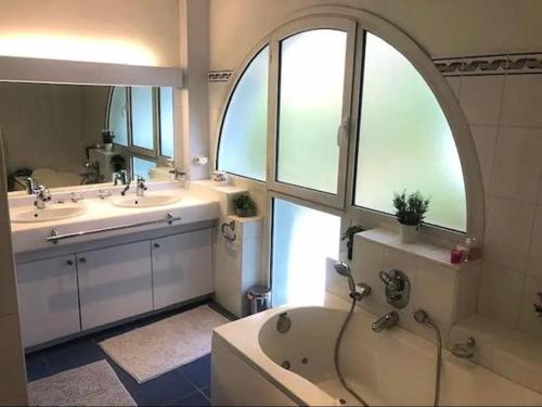 La salle de bains est pourvue de 2 lavabos, d'une baignoire et d'une fenêtre. dans l'établissement Villa Sérénité 4 étoiles sans vis à vis 4ch8p près dune du Pilat Clim piscine, à La Teste-de-Buch