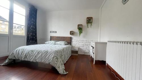 a bedroom with a bed and a desk in it at Appartement spacieux à Caen 65 m² avec balcon vue sur la ville in Caen