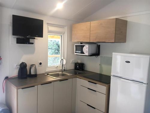 a small kitchen with a white refrigerator and a sink at Camping Cala Llevado in Tossa de Mar