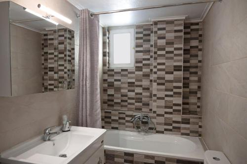 a bathroom with a tub and a sink and a mirror at Efi's apartment in Kalamata