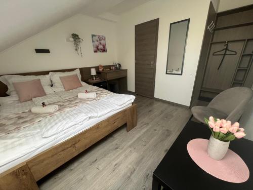 a bedroom with a large bed and a chair at Sophia Apartman Gödöllő in Gödöllő
