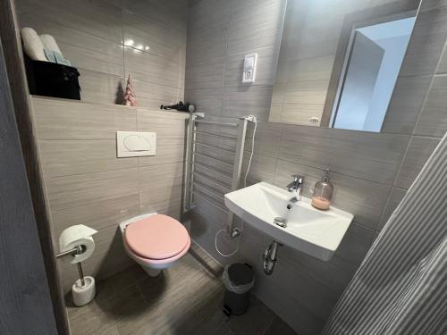 a bathroom with a pink toilet and a sink at Sophia Apartman Gödöllő in Gödöllő