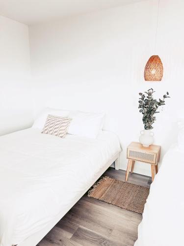 a white bedroom with a bed and a table at À Bon Port in Perce