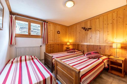 two beds in a room with wooden walls at Chalet Le Choucas N°1 in Levassaix
