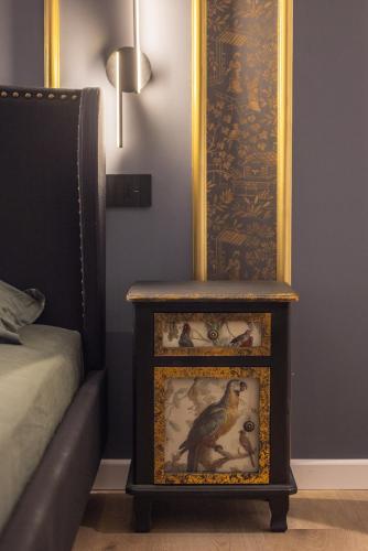 a side table with a bird painting on it next to a bed at ReMia Suites & Leisure in Alassio