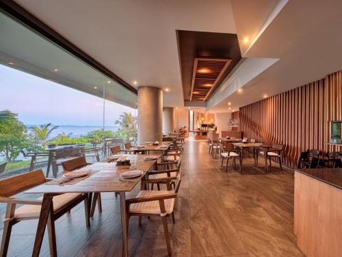 a restaurant with tables and chairs and a view of the ocean at MASON, a member of Design Hotels in Na Jomtien