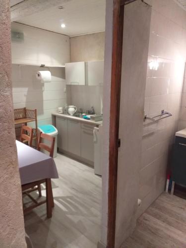 une cuisine avec des placards blancs et une table ainsi qu'une chambre dans l'établissement L oustau des Arênes, à Arles