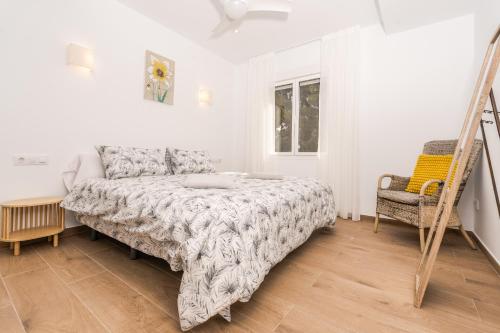 a white bedroom with a bed and a chair at Aparto Almi in Moraira