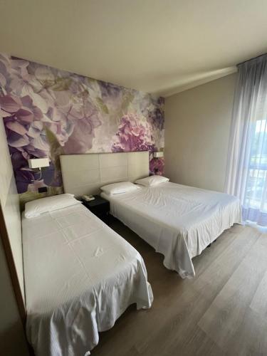 a bedroom with two beds and a painting on the wall at Hotel Parigi 2 & Spa in Dalmine