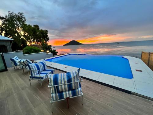 - une piscine avec des chaises et l'océan au coucher du soleil dans l'établissement Escapes, à Cape Maclear