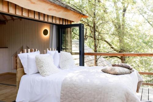 a bedroom with a white bed with pillows on a porch at Dolce et Cabane in Bérat
