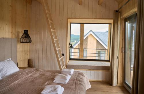 a bedroom with a bed with a ladder and a window at Шале Green Land in Bukovel