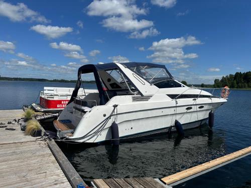 a white boat is docked at a dock at Yachthouse in Plateliai