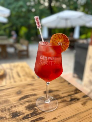 a red drink with an orange slice on a wooden table at Hotel Cortaccia Sanvitale in Sala Baganza