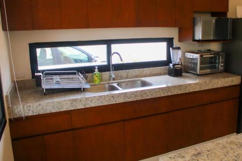 eine Küchentheke mit Spüle und Fenster in der Unterkunft Corcomoran Luxury beachfront house in Telchac Puerto