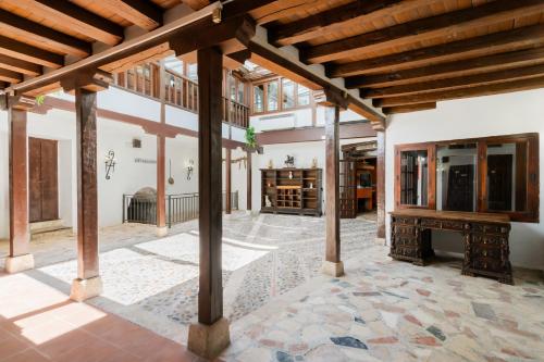 an open living room with a stone floor and wooden ceiling at Hotel La Quinta de Santillán in Chinchón