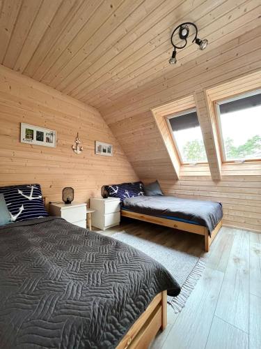 a bedroom with two beds in a wooden cabin at Nowe Domki Letniskowe in Pobierowo