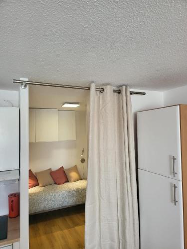 Cette chambre comprend un lit et un rideau. dans l'établissement Résidence Le Pharo, au Cap d'Agde