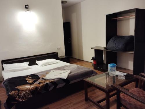 a bedroom with a large bed and a table at New Gulmarg Manali in Manāli