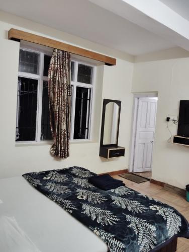 a bedroom with a bed and two windows at New Gulmarg Manali in Manāli