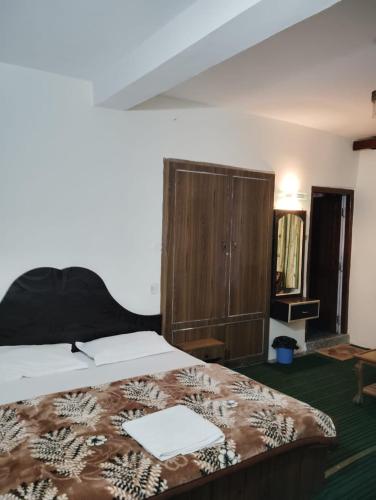 a bedroom with a bed and a wooden cabinet at New Gulmarg Manali in Manāli