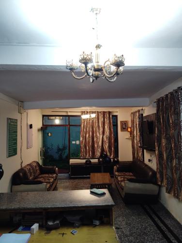 a living room with couches and a chandelier at New Gulmarg Manali in Manāli