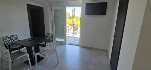 a dining room with a table and chairs and a television at Panorama Apartments in Povljana