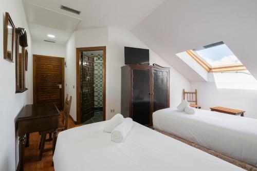 a bedroom with two white beds and a piano at Hotel La Quinta de Santillán in Chinchón
