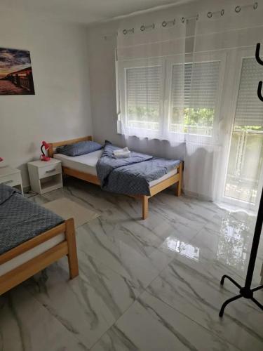 a bedroom with two beds and two windows at Sobe Zimmer & Apartmani Nova Gradiška in Nova Gradiška