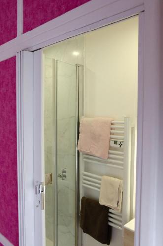 La salle de bains est pourvue d'une douche en verre aux murs roses. dans l'établissement A l'abri des vents, à Saint-Jean-le-Thomas