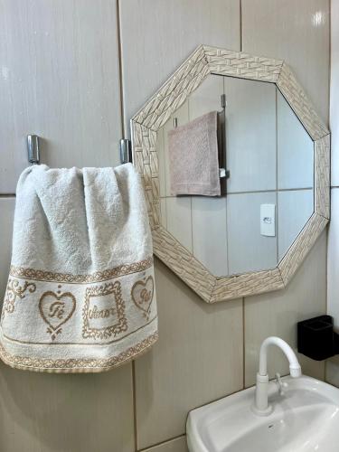 a bathroom with a mirror and a sink at Suítes e PENHA-SC in Penha