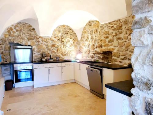 - une cuisine avec des placards blancs et un mur en pierre dans l'établissement Magnifique appartement, à Aregno