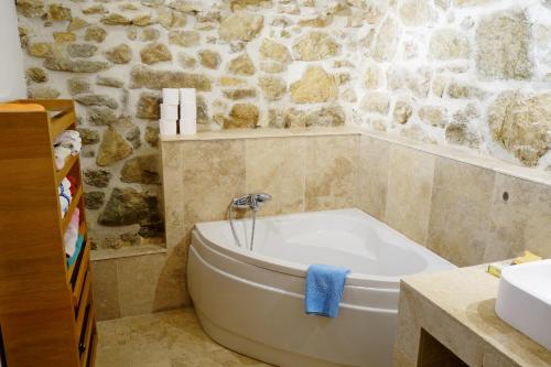 La salle de bains est pourvue d'une baignoire blanche et d'un mur en pierre. dans l'établissement Magnifique appartement, à Aregno