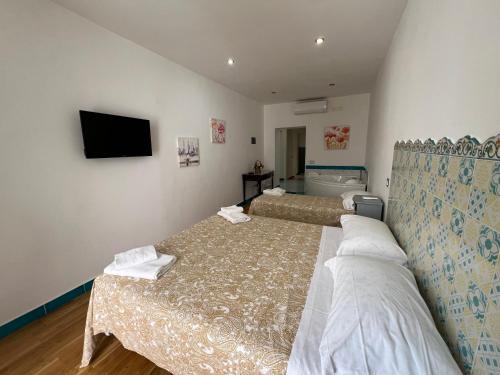 a hotel room with two beds and a flat screen tv at SALERNO COSTA D'AMALFI SUITE in Salerno