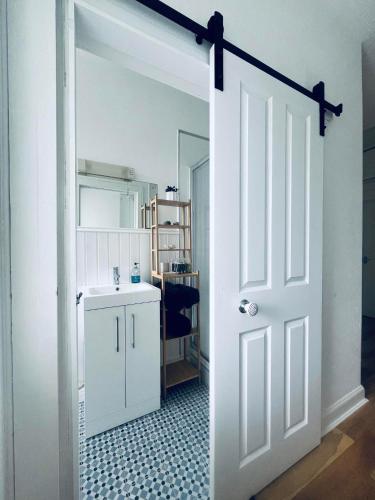 a white door leading into a bathroom with a sink at 7a Seatreat in Kinghorn