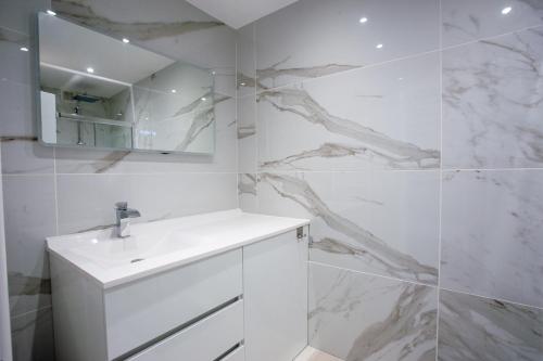 une salle de bain blanche avec un lavabo et un miroir dans l'établissement Smartstay Sun - 100 m de la plage, au Lavandou