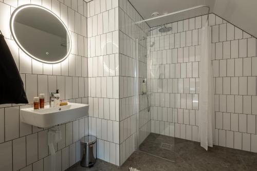 a white tiled bathroom with a sink and a mirror at Unity Malmö - A Studio Hotel in Malmö