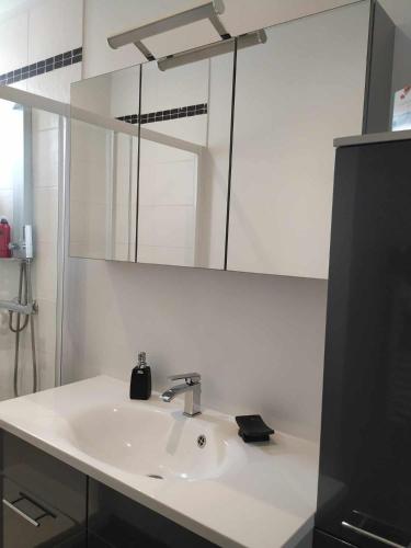 une salle de bain blanche avec un lavabo et un miroir dans l'établissement Chez Marie, à Cancale