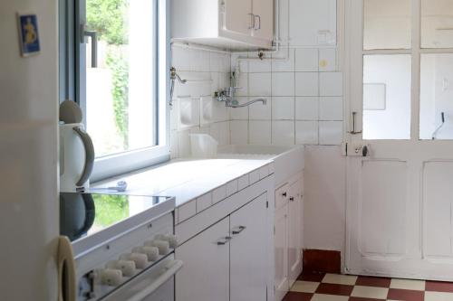 une cuisine blanche avec un évier et une fenêtre dans l'établissement Maison de vacances quartier Arago Les Sables - 8 personnes, à Les Sables-dʼOlonne