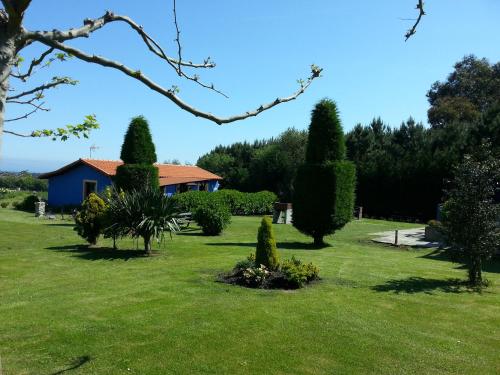 a garden with trees and a house in the background at Apartamentos y Habitaciones Casa Bego in Valdredo