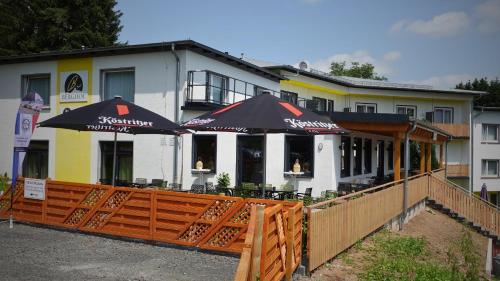 a restaurant with umbrellas in front of a building at Hotel Berghof Wasserkuppe & Gästehaus Fuldaquelle in Gersfeld