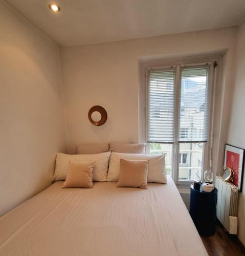 un lit dans une chambre avec une grande fenêtre dans l'établissement Appartement de charme dans les Batignolles, à Paris